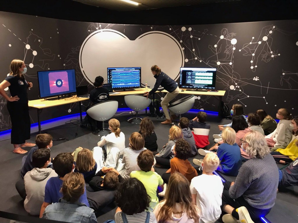 Two female scientists simulating a space weather room to young students