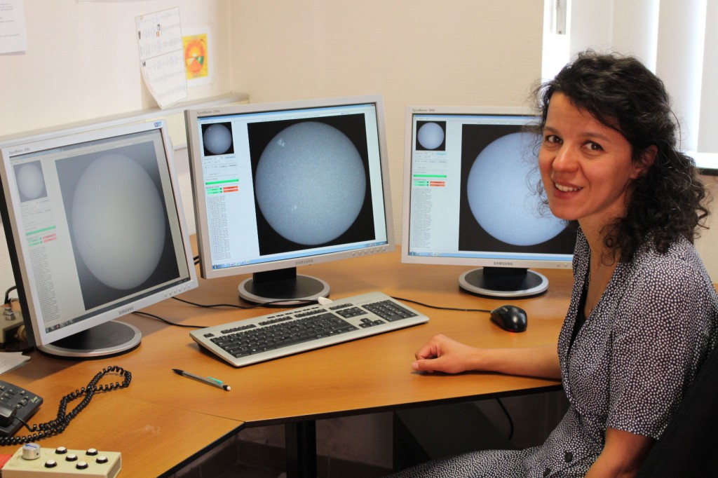 Photo of Sabrina Bechet in the USET control room. The computer screens show the sun in different wavelengths.