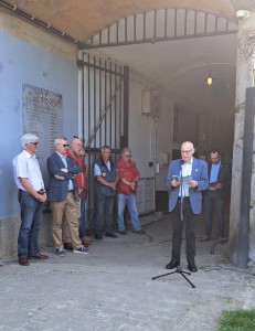 A man behind a microphone giving a speech to a crowd to his right
