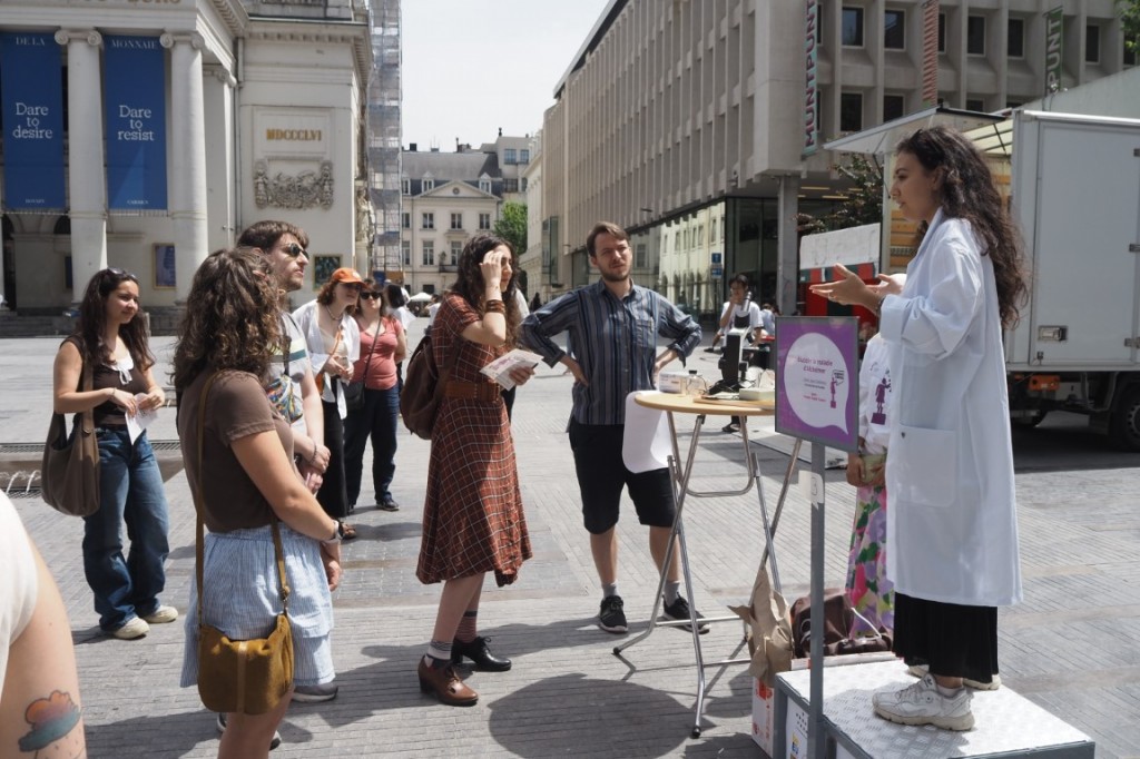 Une femme en blouse blanche sur un podium s'adressant à une foule.